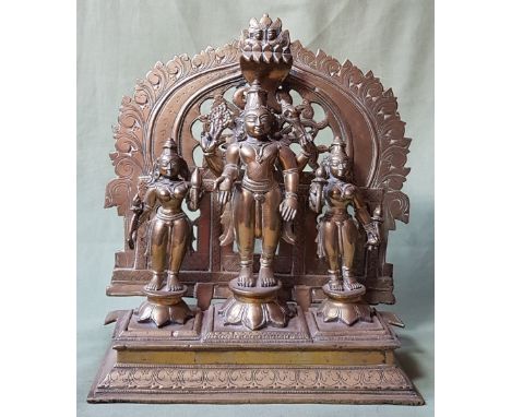 A large Indian brass altar group comprising three figures, the central figure with inset ruby coloured stone, 11" high.