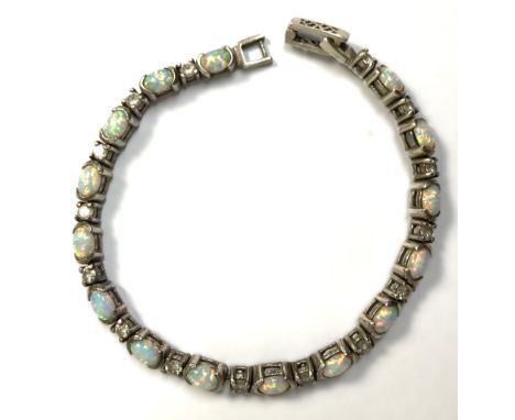 A pretty cabochon opal and silver bracelet, 20th century,   fitted with 15 opals divided by white stone gems, probably CZ, on