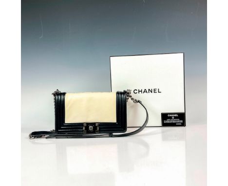 Boasting smooth black and ivory colored leather bag with ruthenium finish metal chain strap. Feature embossed Chanel logo des