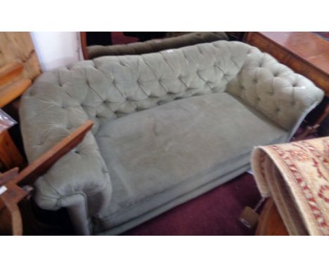 A 5' 10" vintage Chesterfield settee upholstered in pale green button back velour, set on polished wood bun feet with integra