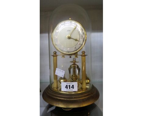 A vintage brass Koma anniversary clock with rotary pendulum under glass dome