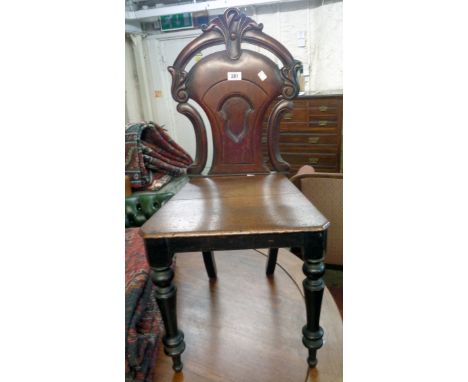 A Victorian mahogany hall chair with stylized shield back, scroll decoration and turned front legs