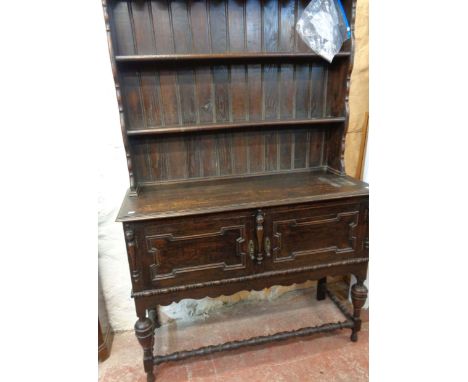 A 4' early 20th Century stained oak two part dresser with two shelf open plate rack over a base with double panelled cupboard