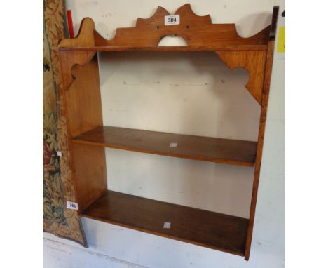 An 18 3/4" early 20th Century varnished oak wall mounted three shelf unit with decorative top