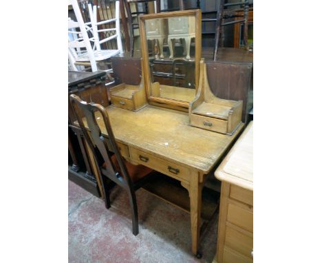 A 3' 6" early 20th Century golden oak dressing table with swing mirror, flanking shelves and trinket drawers over two frieze 