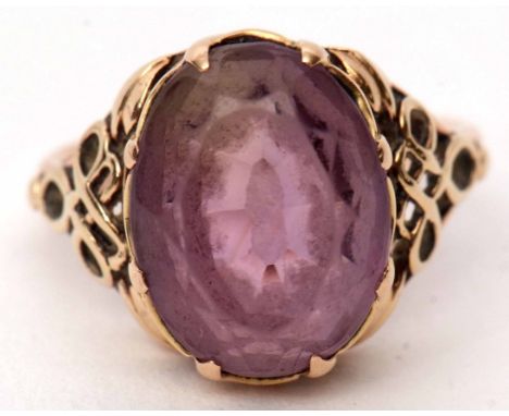 Antique yellow metal and amethyst ring, the pale oval faceted amethyst raised in a coronet mount to scrolled pierced and plai