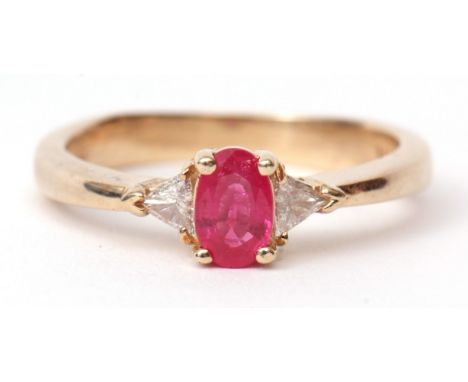 Modern ruby and diamond ring, the oval shaped faceted ruby raised between two small brilliant cut diamonds, stamped 14K, size