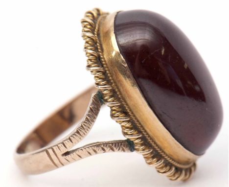 Antique large cabochon garnet set ring, bezel set in a yellow metal scroll bead mount having split shoulders to a plain shank