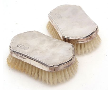 Two George VI silver backed hair brushes, each with shaped and engine turned backs with initialled cartouches, London 1950, m