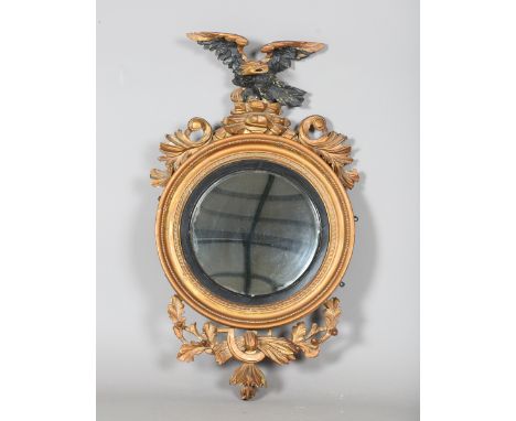 A Regency gilt and ebonized convex wall mirror with a carved eagle surmount and foliate crestings, height 85cm, width 48cm (l