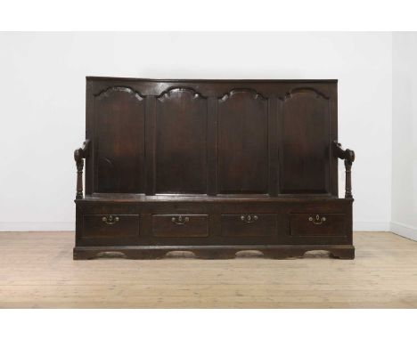 A carved oak settle,17th century, the gadrooned carved top rail over a stiff-leaf arcaded frieze and four arched panels, swep