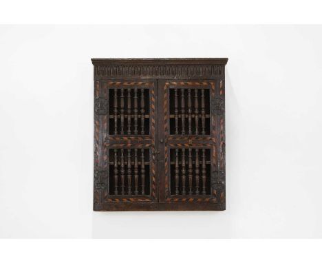 A Charles I oak and inlaid ventilated livery cupboard,17th century, the moulded flat cornice over a pair of intarsia banded d