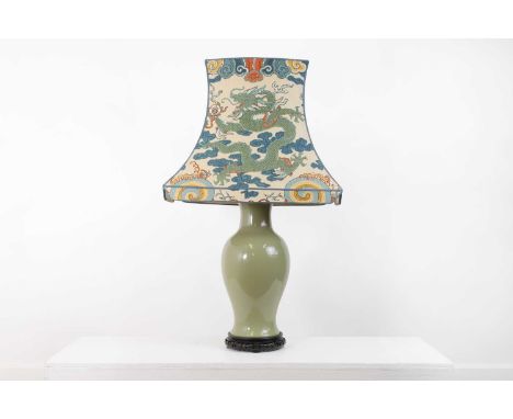 A celadon-glazed pottery lamp,of recent manufacture, Chinese, of baluster form on a hardwood base, with a linen-covered shade