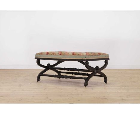 An ebonised wooden stool,19th century, the rectangular seat upholstered with needlepoint fabric, raised on 'X' frame supports