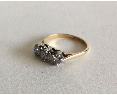 A diamond three stone ring in 18 carat gold and platinum claw mount. Approx. 3 grams. Est. £100 - £150.