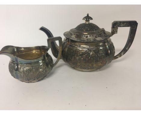 A silver Chinese tea pot decorated with bamboo with matching milk jug 843 grams..