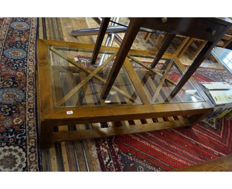 A modern large oak coffee table, with two glass inset tops and slatted shelf beneath.