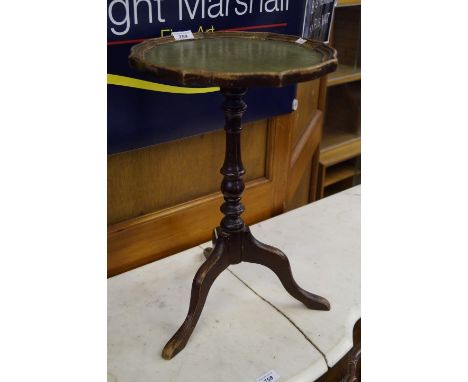 A reproduction mahogany veneered tripod coffee table, with green leather inset top.