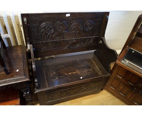 A mid 20th Century dark oak monks bench, of small proportions, having carved decoration.