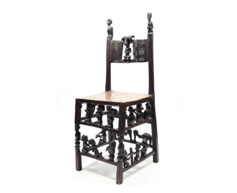 A Chokwe chair Angola wood and hide, carved with figures in daily and ritual pursuits, birds, bats, monkeys and a snake, the 