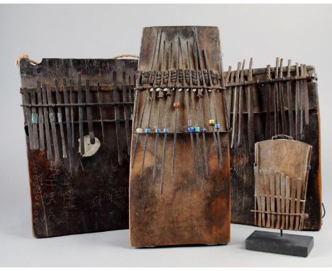 Four East African mbiras wood and metal; one with beads, another decorated with circles and dots and inscribed various names,