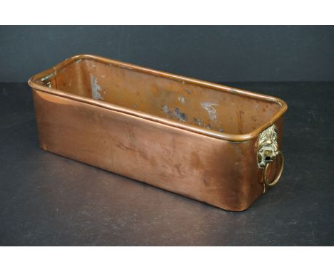 An antique copper planter with brass lion head handles. 