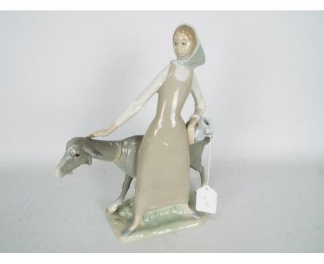 Lladro - A figural group with a girl holding a pitcher beside a goat, # 4590, approximately 27 cm (h).Condition Report: Appea