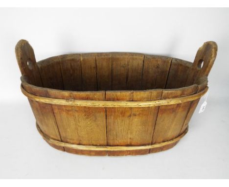 A vintage, oval wooden trough, approximately 33 cm x 60 cm x 37 cm.