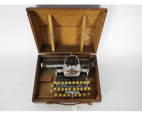 A Blick Aluminium Featherweight typewriter contained in wooden carry case.