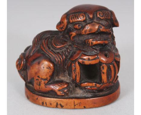 A JAPANESE MEIJI PERIOD CARVED WOOD NETSUKE OF A SHI-SHI, its chin resting on a brocaded ball, 1.75in wide & 1.6in high.