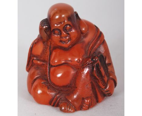 A SMALL AMBER STYLE NETSUKE OF BUDDHA, the base with an engraved mark, 1.8in high.