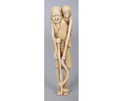 A JAPANESE MEIJI PERIOD MARINE IVORY NETSUKE OF A TALL STANDING MAN, the man’s feet forming the himotoshi, with a monkey on h