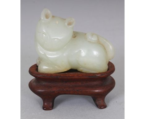 A SMALL 18TH CENTURY CHINESE CELADON GREEN JADE MODEL OF A CAT, together with a fitted wood stand, the cat’s head turned to o
