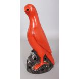 A 19TH CENTURY CHINESE CORAL GLAZED PORCELAIN MODEL OF A PARROT, perched on pierced rockwork, 11in
