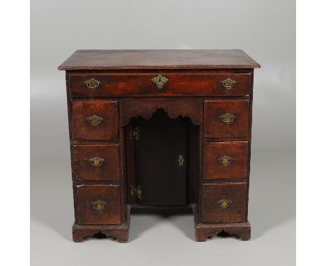 the moulded top above an arrangement of seven drawers around the kneehole cupboard enclosing a shelf and drawer, height 84cm,