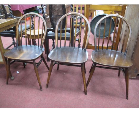 Three Dark Ercol Chairs, with hooped backs, tail supports, solid seats, on splayed legs.