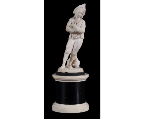  A Dieppe ivory figure of a peasant boy,   late 19th century,  standing with folded arms and tree trunk support (damaged), on