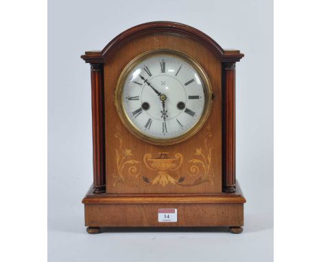 An early 20th century walnut cased eight-day mantel clock, the enamel dial showing Roman numerals, flanked by reeded columns 