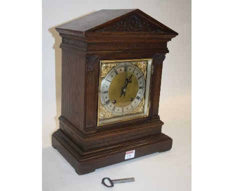 A circa 1900 oak cased mantel clock, of architectural form, the silvered dial showing Roman numerals, having eight-day moveme