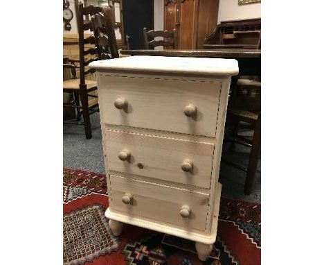 A light pine three drawer bedside chest