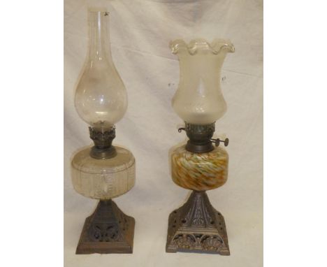 An Edwardian oil lamp with cast iron square base and mottled glass reservoir and one other iron and glass oil lamp (2)