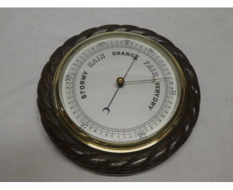 A good quality aneroid barometer with circular ceramic dial in oak rope twist case