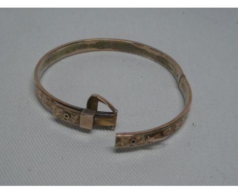 A 9ct gold circular bangle with engraved decoration and buckle clasp