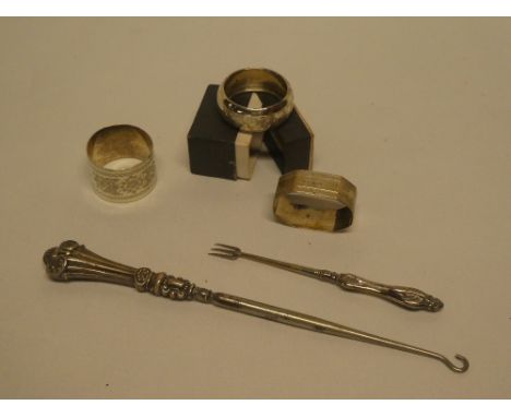 Three various silver napkin rings, a silver handled button hook and one other condiment fork (5)