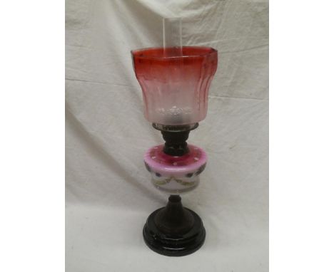 A Victorian brass mounted oil lamp with opaque glass reservoir and cranberry tinted glass etched shade