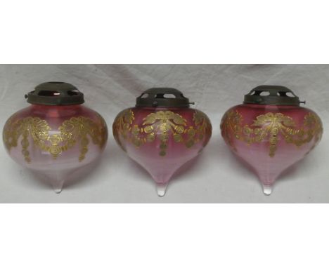 Three matching Arts and Crafts cranberry-tinted glass light-shades with gilt painted decoration 8" long