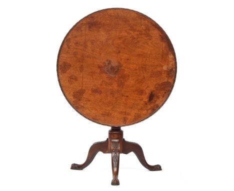 A George III mahogany tripod table, the circular tilt-top with moulded edge, on a turned stem on shell and bell flower carved