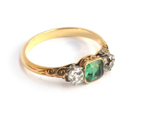 A gold ring set with a cushion cut emerald, approx. 0.6 carats, and two diamonds approx. 4mm diameter, the band with foliate 