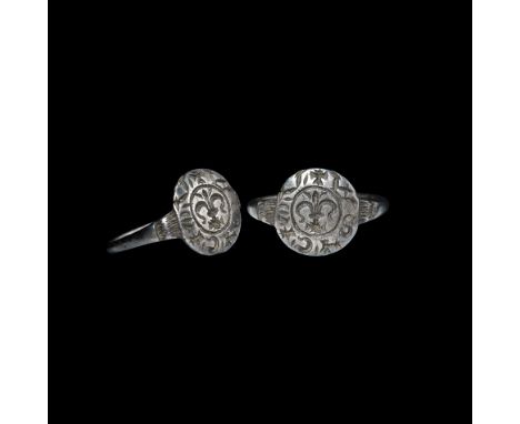 12th-13th century AD. A silver finger ring with disc bezel, central fleur-de-lys motif, enigmatic surrounding legend '+ W S T