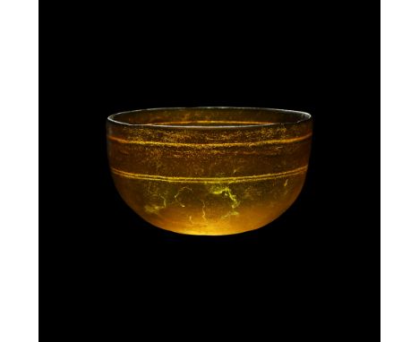 3rd-1st century BC. An amber-coloured hemispherical glass bowl with circumferential rotary grinding marks on the interior, sh